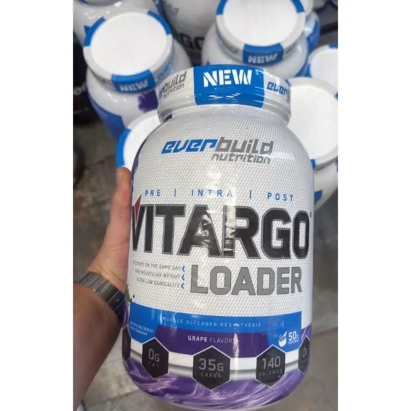 قوطی مکمل کربوهیدرات ویتارگو لودر اوربیلد نوتریشن (Everbuild Vitargo Loader) با طعم انگور در دست با پس‌زمینه قوطی‌های مکمل